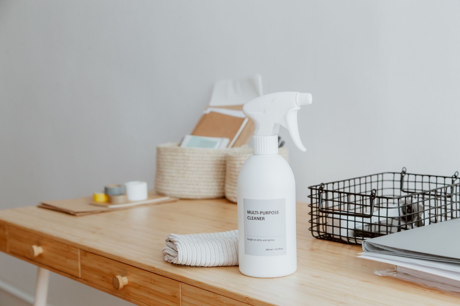 Minimalist desk with a focus on a multipurpose cleaner, office supplies, and storage solutions