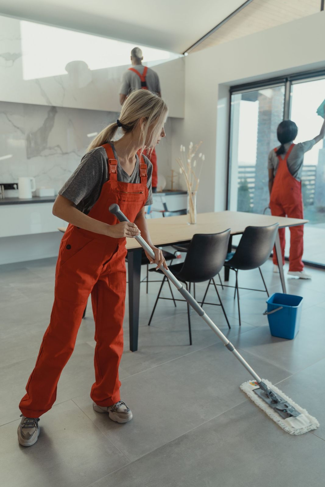 Cleaning team in red overalls mopping and sanitizing a modern home interior